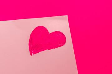 Heart painted with pink lipstick on a white sheet on a pink background. High quality photo