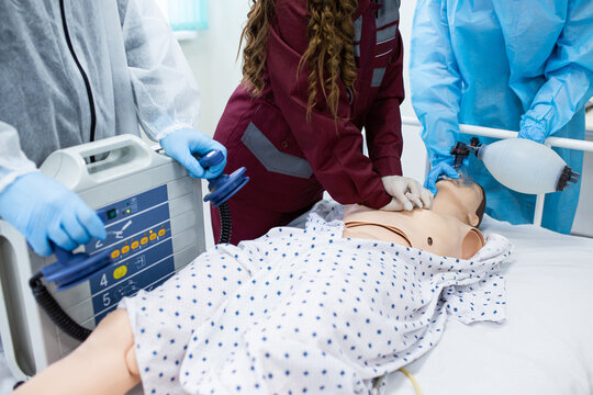 First aid for artificial respiration with the concept of AED training. Paramedic demonstrates cardiopulmonary resuscitation on a mannequin to medical students and nurses Emergency services profession