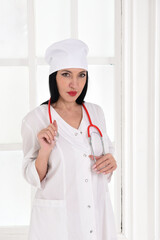 A female therapist with a stethoscope in the clinic against the background of windows
