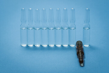 Medical ampoules are on the table in a row, one of a different color.