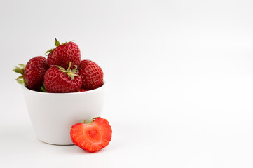 In a white dish, ripe strawberries on a light background with space for writing text.