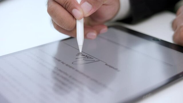 Close up businessman hand working electronic Signature on Tablet by Stylus. Write business agreement of contract. Man signing contract on tablet. Business and technology concept.