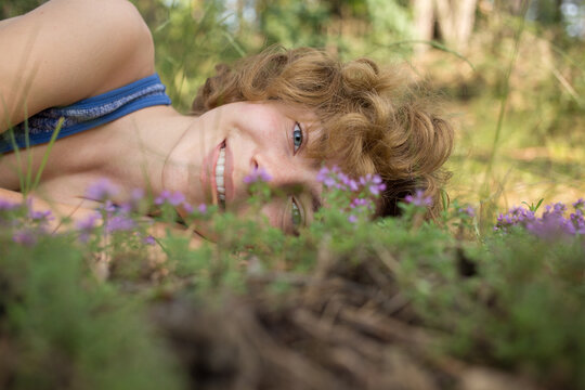 face of teenage girl lying on grass with small flowers, enjoying nature outdoors. Cute young woman is resting in park. spring, summer, sunbathing. dreams, harmony, replenishment of vitality. earth day