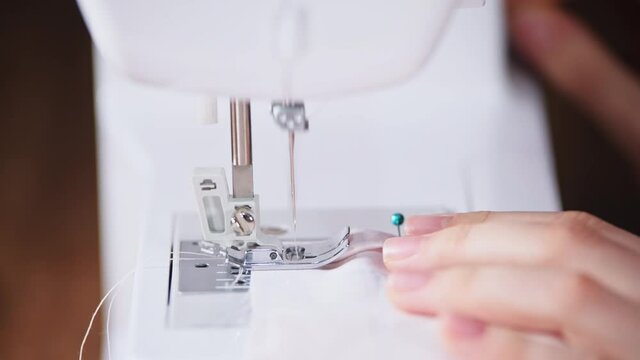 A tailor sews linen on a typewriter. The needle stitches the fabric close-up