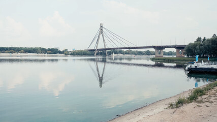 bridge over wide river under cloudy sky.