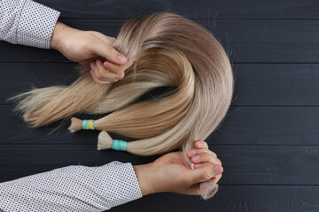 The male hand holds sections of hair for extension.Photography from above. © Bidzilya