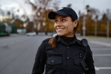 Portrait of smiling police woman on street - Powered by Adobe