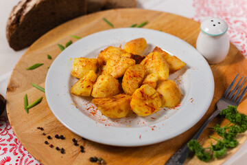 baked potatoes with a crust on a white plate and a wooden background in the cafe Russian cuisine