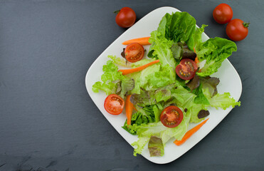 Healthy vegetable salad of fresh tomatoes,lettuce,carrot on plate. Diet menu.