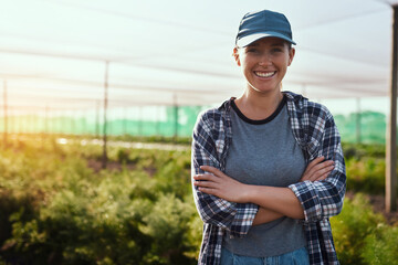I run a fruitful farm. Cropped portrait of an attractive young female farmer standing with her arms...