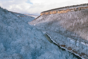 Aerial view of Plateau Lago-Naki mountain twisted road in the winter and driving car. Epic, snowy white winter and snow capped forest.