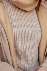 Knitted trendy beige sweater. Feminine style and beauty. Girl in a woolen pullover close-up