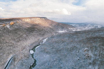 Aerial view of Plateau Lago-Naki mountain twisted road in the winter and driving car. Epic, snowy white winter and snow capped forest.