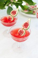 Red drink with ice. Alcoholic beverages decorated with fresh fig fruits on white background. Campari aperol drink