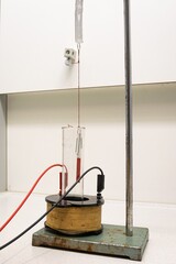 Magnet hanging from a spring vibrates through an alternating magnetic field through copper...
