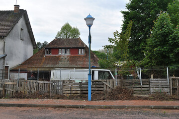 Old Building with Abandoned Van and Lamppost beside Car Park 