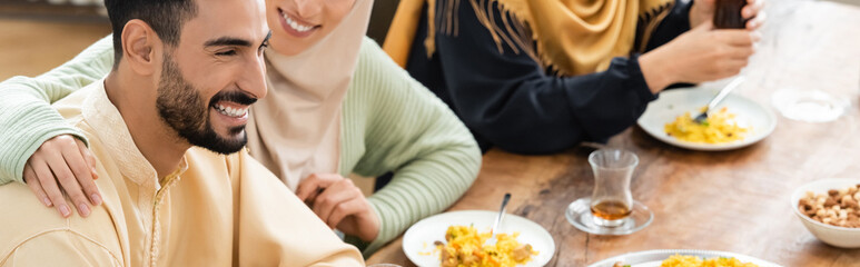 young arabian man smiling during dinner with muslim family, banner.