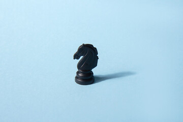 Black chess knight on a blue background. Abstract background. Chess piece. Concept of leadership, loneliness