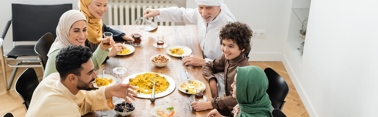 high angle view of happy multiethnic muslim family having dinner at home, banner.