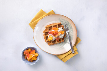 Fresh made waffles with pudding and oranges on bright neutral background. Healthy dessert, tasty homemade breakfast. Vegan, gluten free waffles.