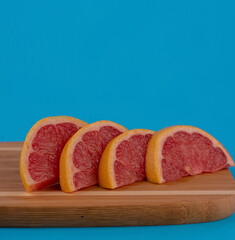 Grapefruit cut into slices. Grapefruit lies on the board of the back boards of blue color. Red grapefruit.