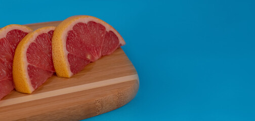 Grapefruit cut into slices. Grapefruit lies on the board of the back boards of blue color. Red grapefruit.