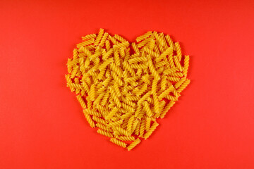 Pasta in the shape of a heart on a red background.	
