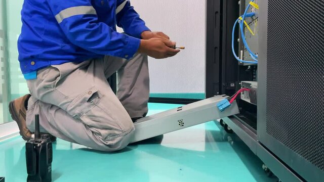 Technician installing and test UPS battery to electrical equipment control cabinet, technology and service working concept.