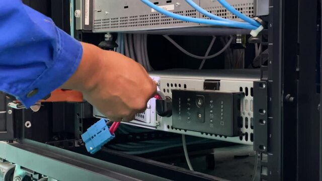 Technician installing and test UPS battery to electrical equipment control cabinet, technology and service working concept.