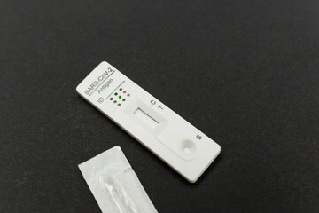 Corona rapid antigen test and swab stick on black background