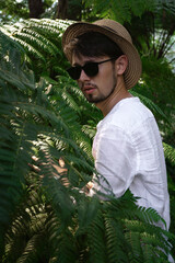 a young man in a straw hat makes his way through the thickets of the jungle