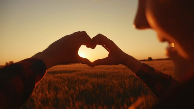 heart. girl with her hands shows a heart symbol at sunset silhouette in a park in nature. charity healthy love concept. hand gesture sun shows heart symbol silhouette. donate community concept