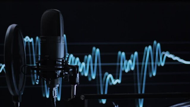 Micr&oacute;fono color negro, profesional en un estudio de grabaci&oacute;n. De fondo se ven ondas de sonido pasando mientras el microfono se mueve