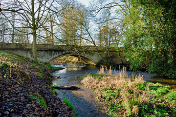 River flowing through old stone arched bridge, winter countryside