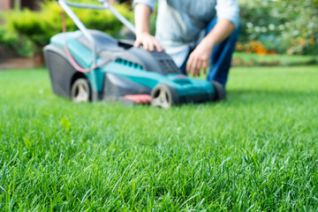 Man with lawn mower going to trim grass