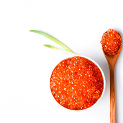 Red caviar in a wooden cup on a grey background with a spoon.