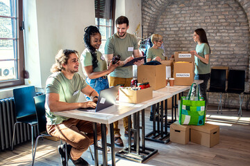 Group of volunteers with working in community charity donation center.