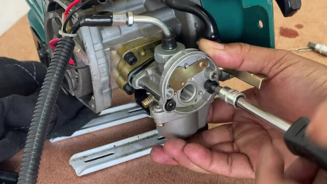 A young man is repairing a small two-stroke engine used for farming. disassemble the parts cleaning the carburetor Reassemble and test 