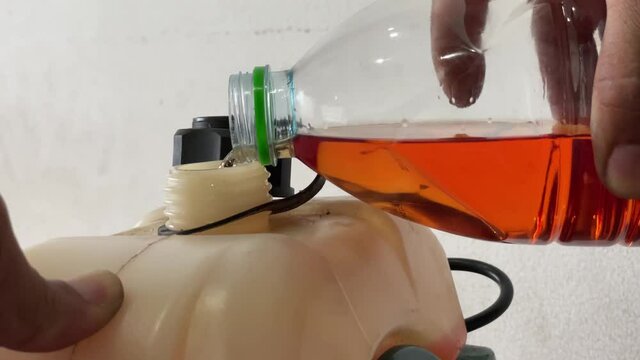 Video Close Up Hands of a man filling up the oil on a 2-stroke engine used in agriculture.