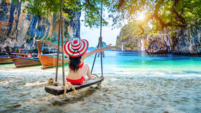 Woman in bikini relaxing on swing at Ko lao lading island, Krabi, Thailand.