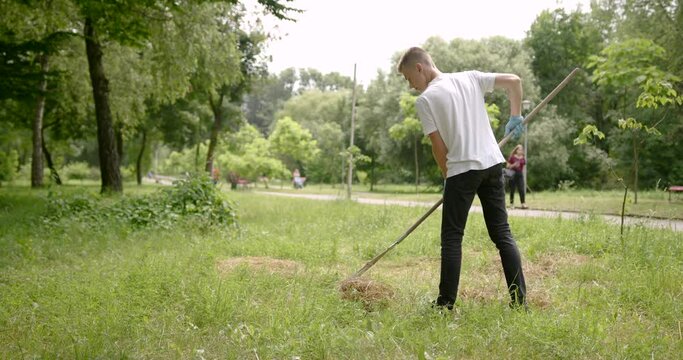 Boy volunteer picks up a trash in a park