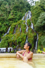 Vertical view of latin american woman at thermal springs in Colombia. Cropped view of woman at jungle waterfalls in Santa Rosa Cabal valley. Colombia travel destination and relax concept.