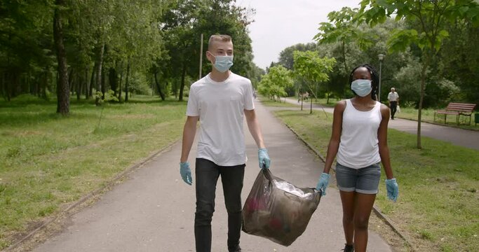 Teenage volunteers carry trash bag in a park
