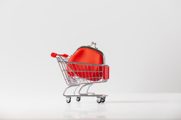 Metallic shopping cart trolley and Red Coin Purse on light gray background with copy space