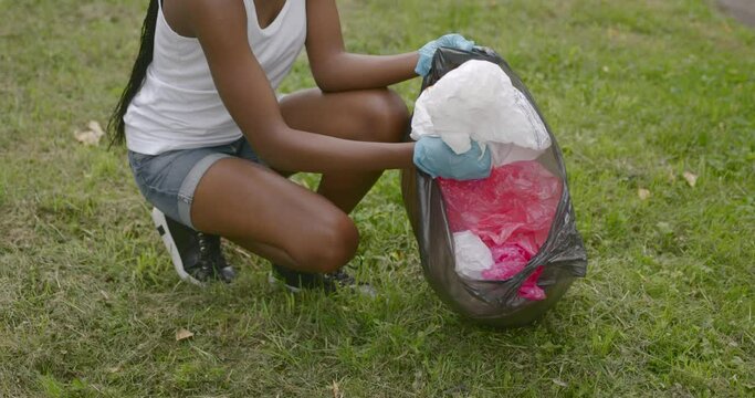 Teenage black girl pick up trash at park