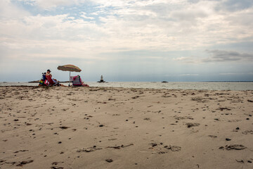 Family beach picnic with umbrellas on a cloudy day near Newport, Rhode Island