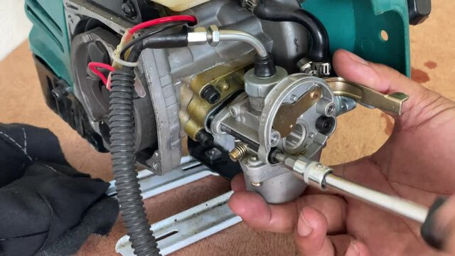 A young man is repairing a small two-stroke engine used for farming. disassemble the parts cleaning the carburetor Reassemble and test 