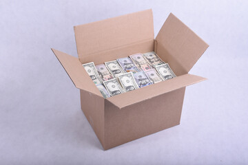 Cardboard packing box full of dollar bills on a white background
