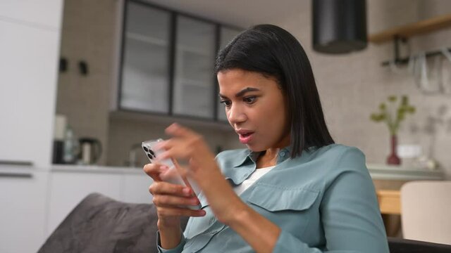 Overjoyed woman looking at phone screen, celebrating success. Excited satisfied young female holding smartphone, reading good news in message, lottery win, shopping offer