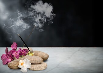 Smoke from burning incense sticks standing on holder with flowers